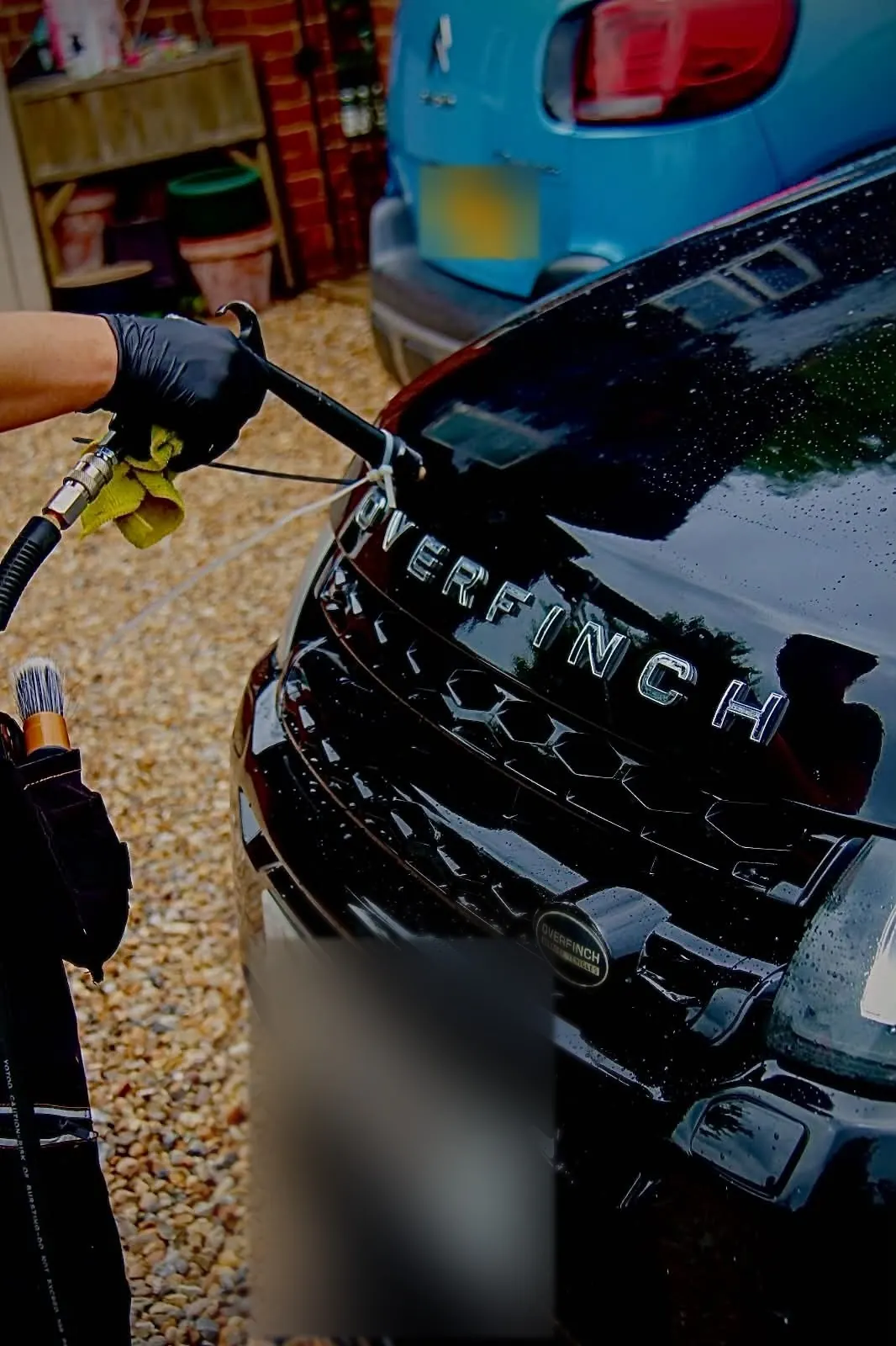 Rinsing the grille and front bumper of a black Range Rover Evoque during an exterior detail