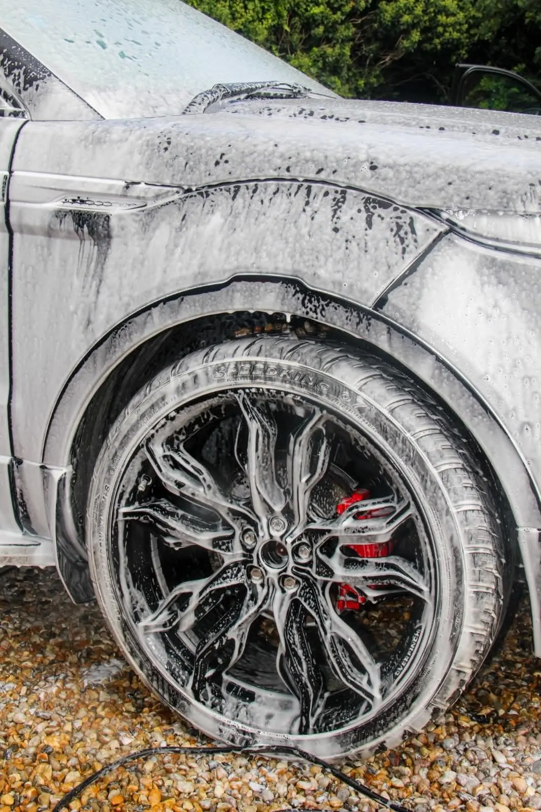 Snow foam covering the front wheel, arch and tyre of a black Range Rover Evoque