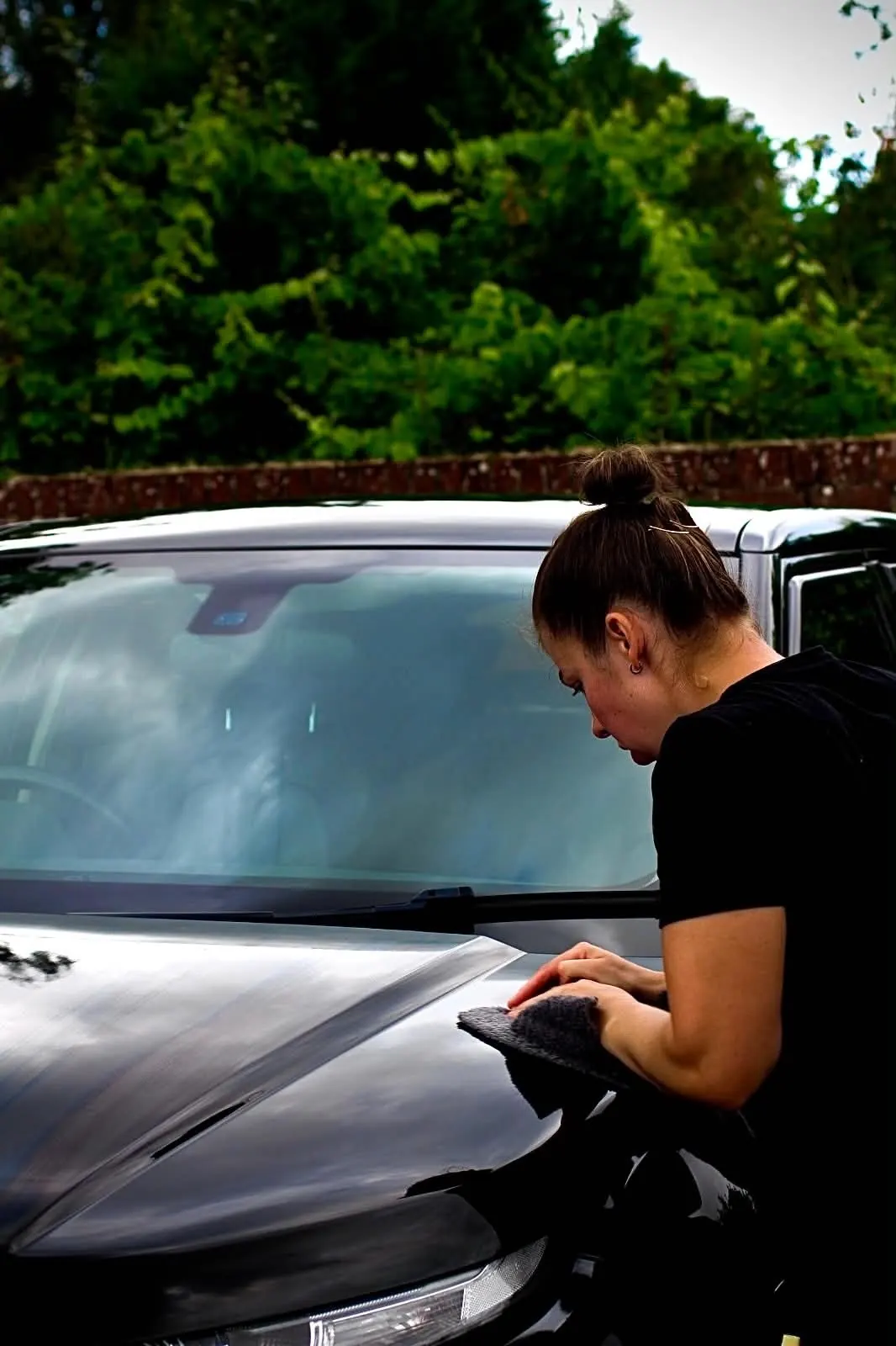 Drying the windscreen and bonnet of a black car with a microfibre towel